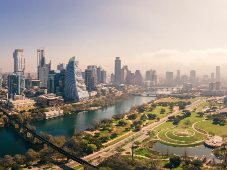A city skyline with modern buildings along a river and a large green park with circular pathways. water damage restoration in Horizon City TX