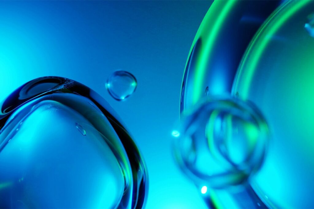 Close-up of translucent blue and green liquid bubbles against a blue background.