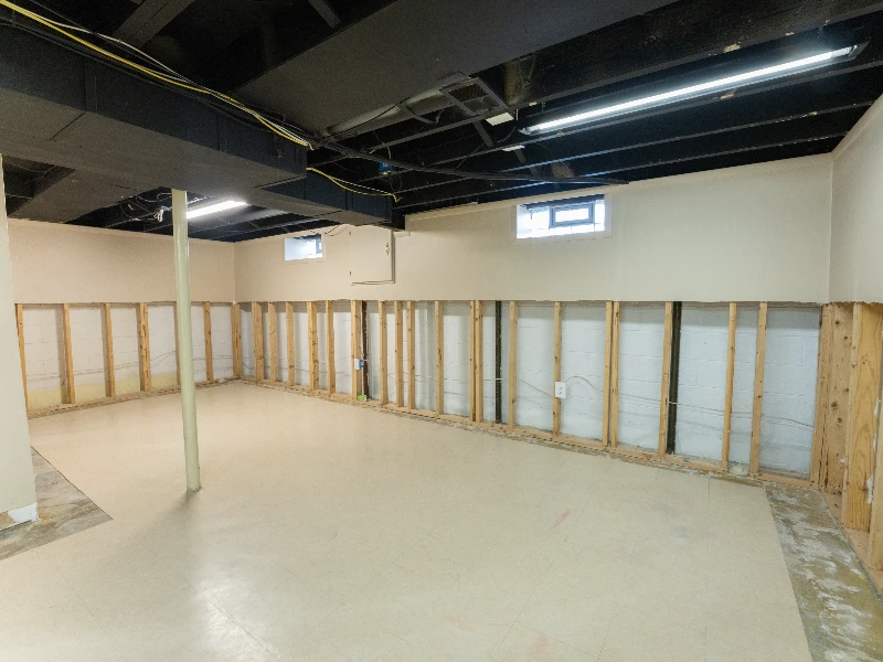 Unfinished basement with exposed wooden wall studs and a support column. commercial water damage restoration